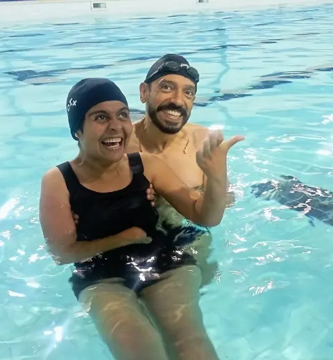 Participante e professor na piscina, sorrindo