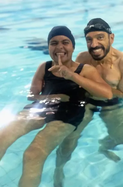 Participante e professor na piscina, sorrindo