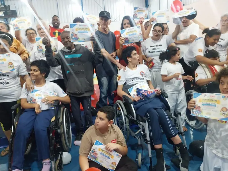 Alunos e familiares com certificados, alguns em cadeira de rodas
