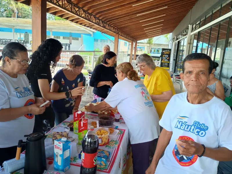 Voluntários e participantes em torno da mesa de lanche, de camiseta do projeto