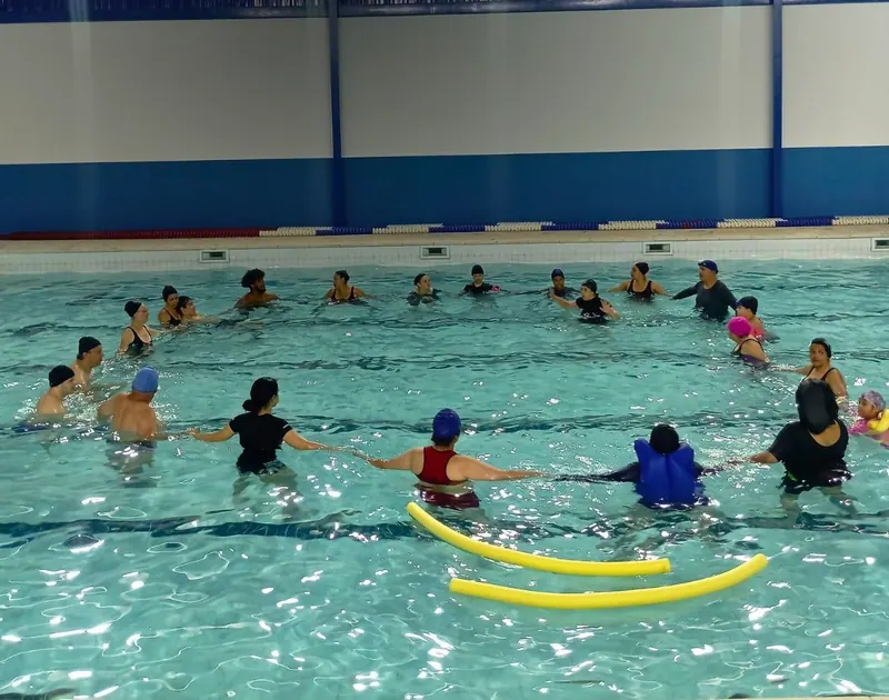 Grupo em roda de mãos dadas numa piscina coberta