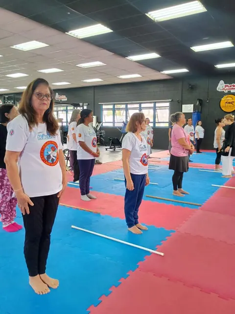 Aula de pé no tatame azul e vermelho, em fila